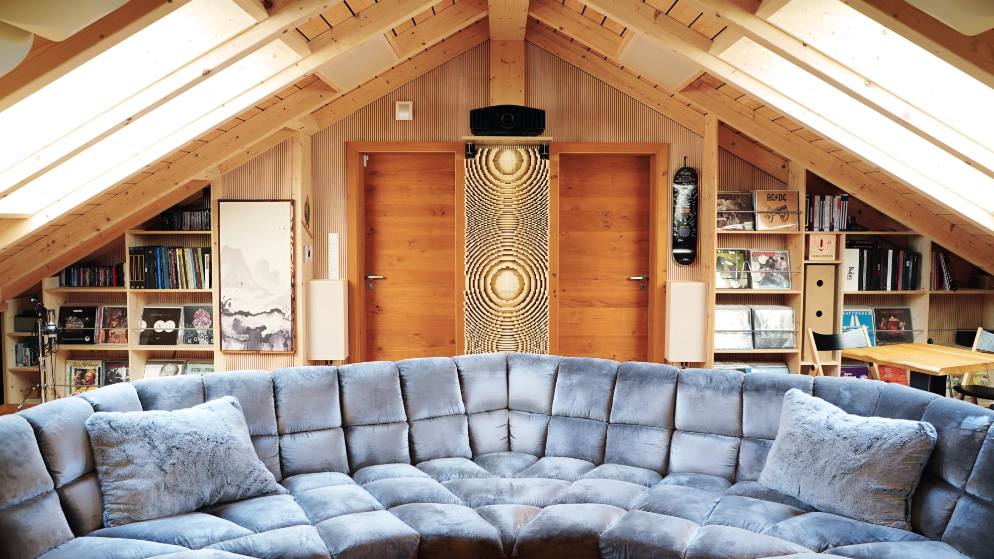 Hörraum von Audio-Freak mit akustischer Optimierung – Blick von der Anlage auf das Sofa, dahinter Regale, Beamer, großer Diffusor und Wände mit Lignotrend-Elementen